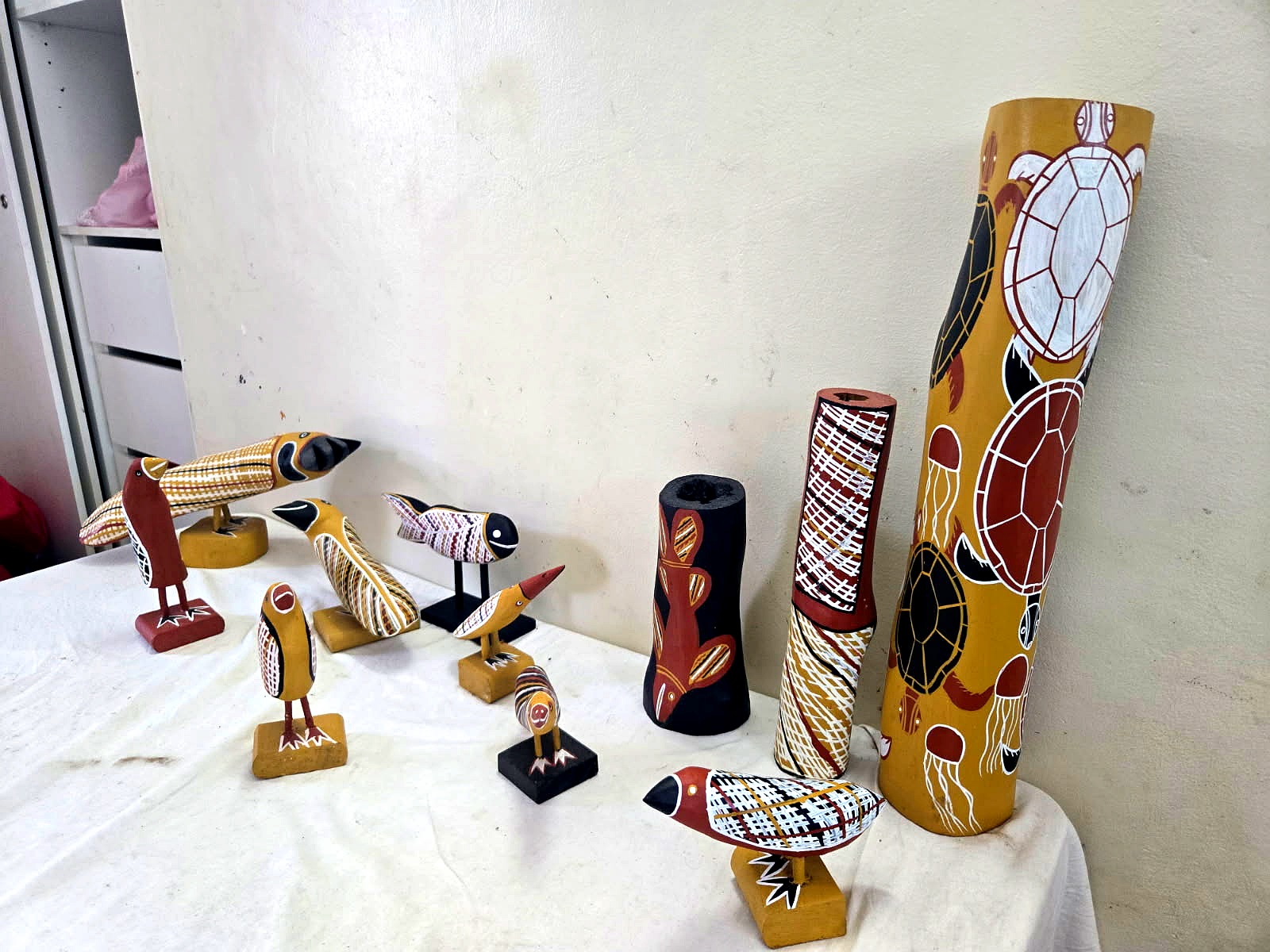 Collection of Yolŋu carved birds, painted cylinders and turtle artwork