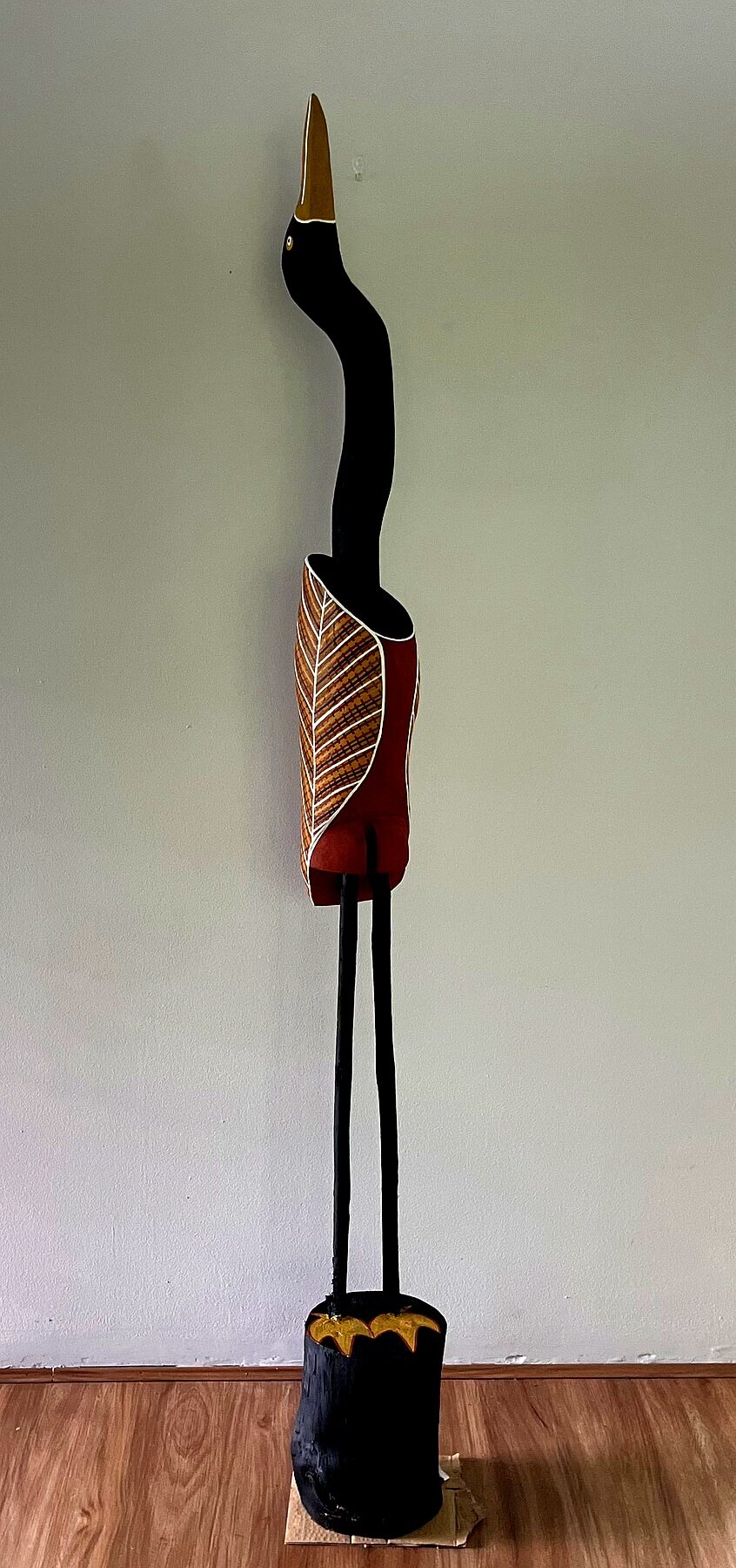Tall dark Yolŋu carved Jabiru bird sculpture with rarrk wing detail